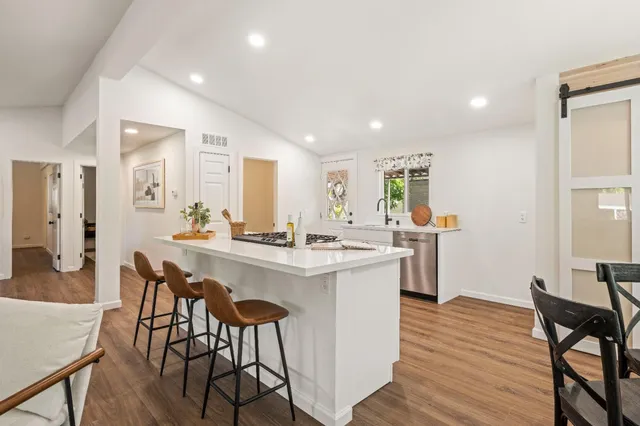 a kitchen with a dining table chairs wooden floor and appliances