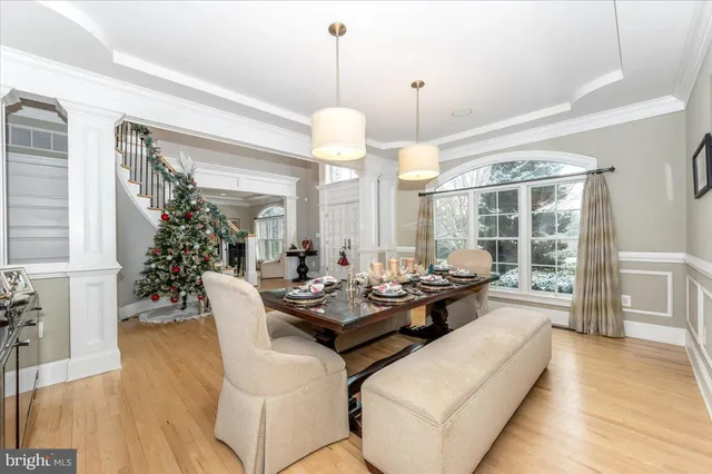 a dining room with wooden floor a chandelier a wooden table and chairs
