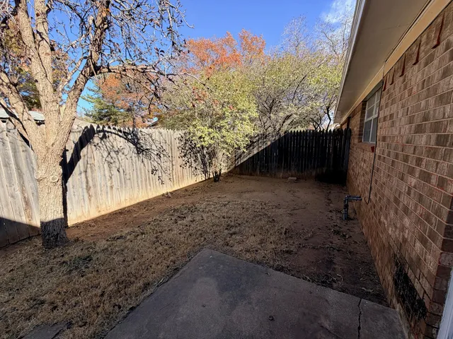 a view of a yard with wooden fence