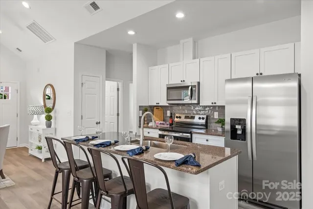 a kitchen with granite countertop a refrigerator a stove a sink cabinets and a dining table