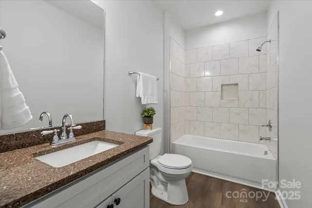 a bathroom with a granite countertop sink a toilet and bathtub