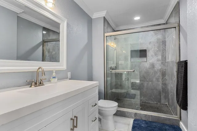 a bathroom with a shower sink vanity mirror and toilet