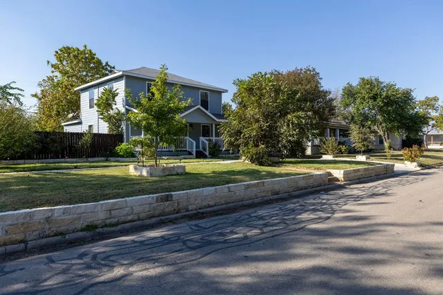a view of a house with a big yard and large trees