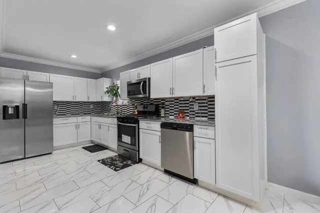 a kitchen with white cabinets and stainless steel appliances