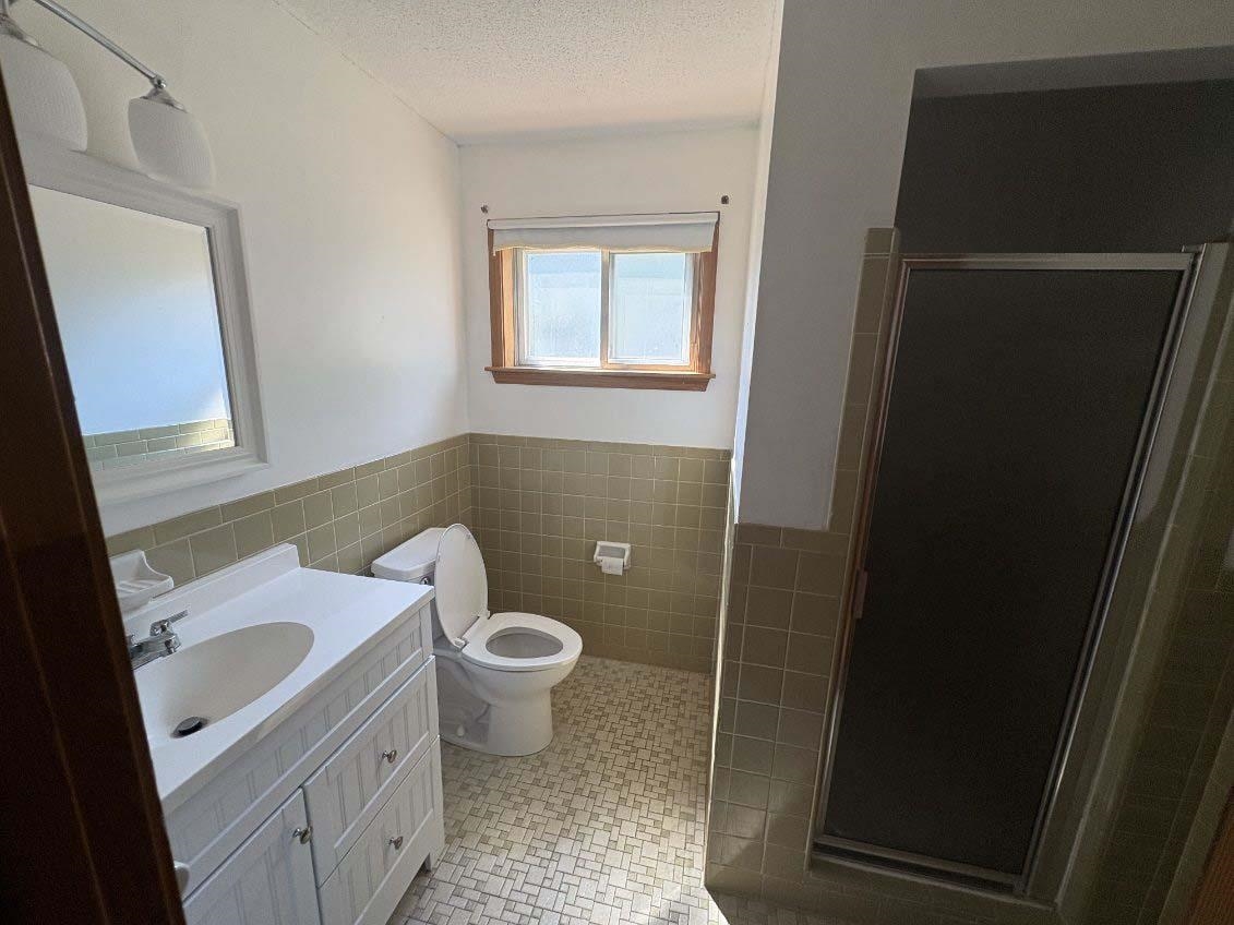 8355 Craven Road Bartlett, TN 38002 - Photo 13 of 28 Bathroom with vanity, a shower stall, tile walls, a textured ceiling, and wainscoting