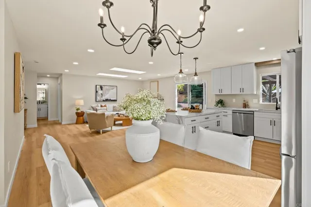 a kitchen with stainless steel appliances granite countertop a sink a stove and a dining table with white cabinets