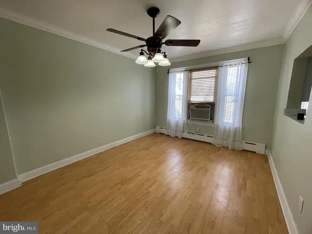 an empty room with wooden floor chandelier fan and windows
