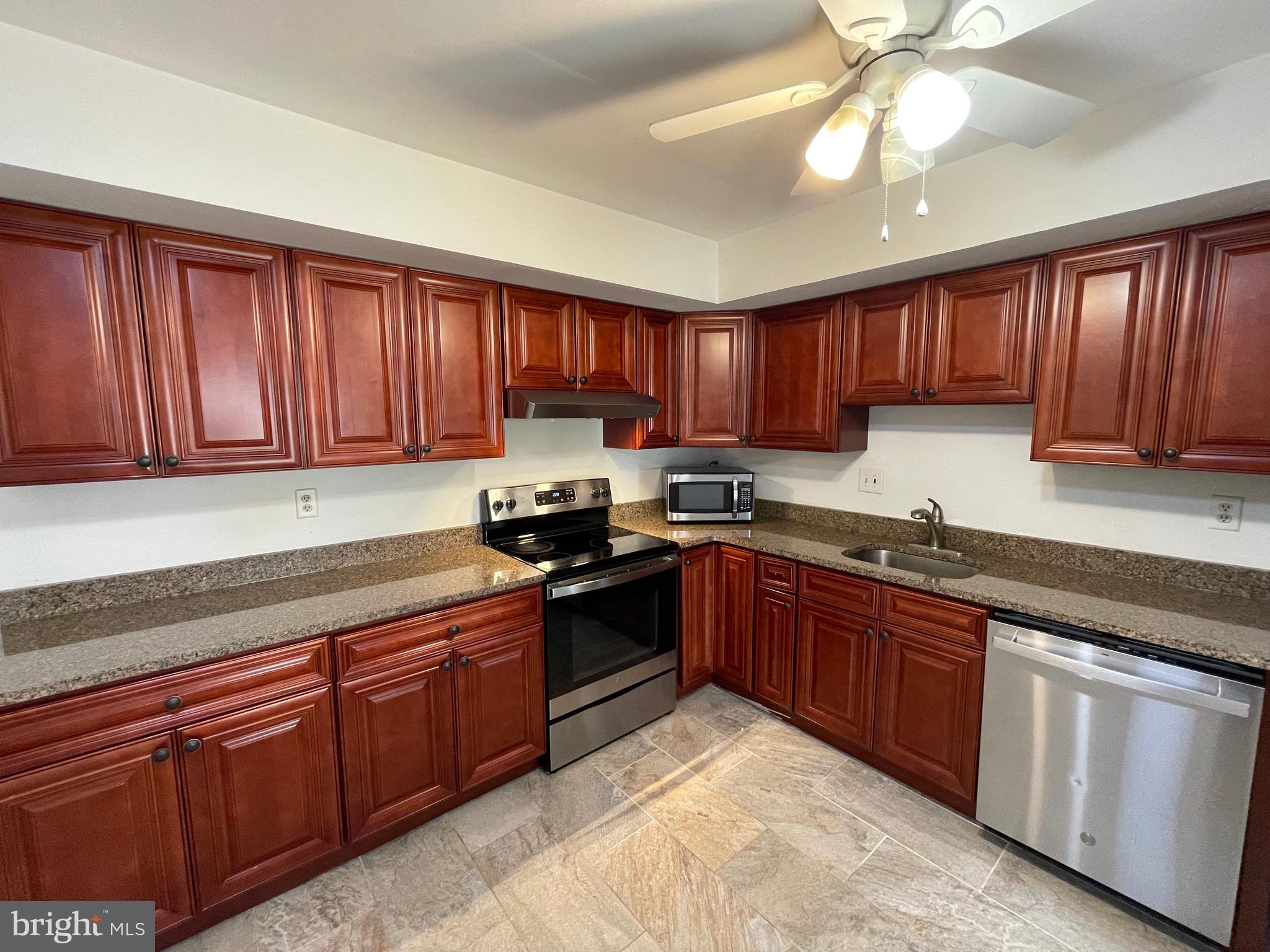 3314 Roxbury Road Hatfield, PA 19440 - Photo 6 of 26 a kitchen with stainless steel appliances granite countertop wooden cabinets a stove a sink and a window