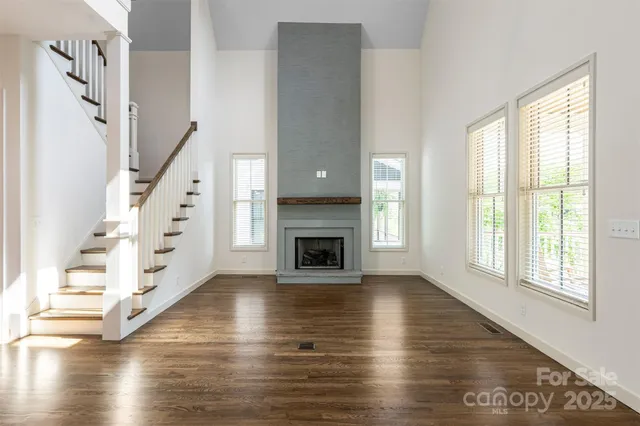a view of an empty room with wooden floor fireplace and a window