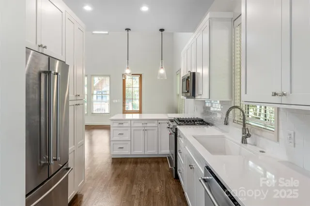 a kitchen with stainless steel appliances granite countertop a sink refrigerator and cabinets