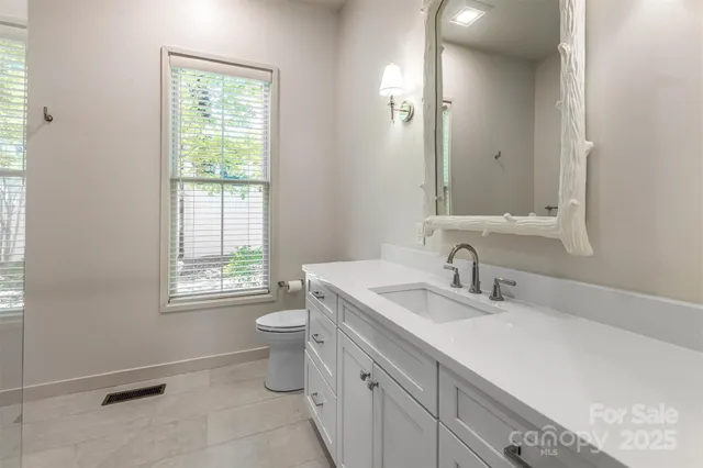 a bathroom with a double vanity sink toilet and a mirror