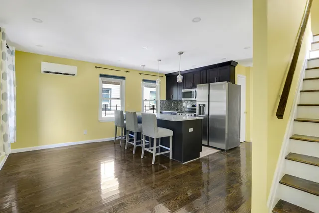 a kitchen with stainless steel appliances a dining table chairs and wooden floor
