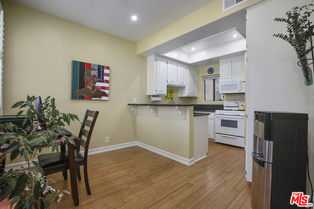 8110 Manitoba Street, Unit 104 Playa del Rey, CA 90293 - Photo 3 of 17 a kitchen with stainless steel appliances a microwave a stove a table and chairs