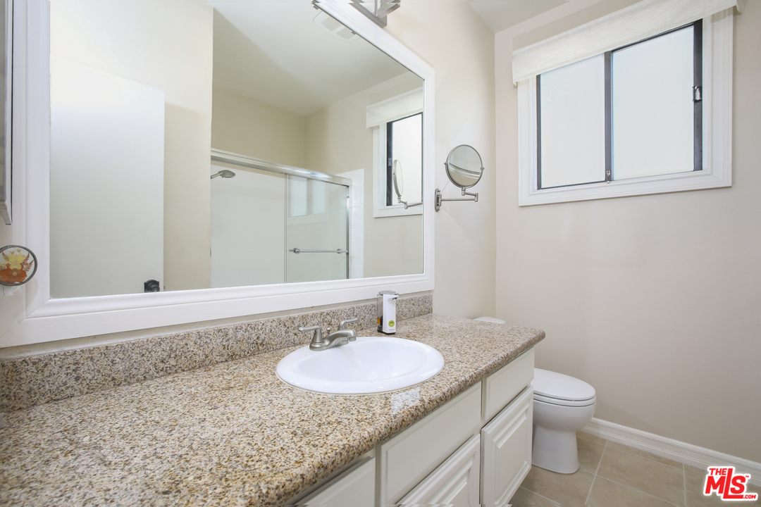 8110 Manitoba Street, Unit 104 Playa del Rey, CA 90293 - Photo 10 of 17 a bathroom with a granite countertop sink a toilet and a mirror