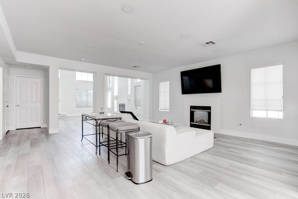 1 Rising Sun Court Henderson, NV 89074 - Photo 12 of 47 Natural light illuminates an open-concept living space with sleek flooring and a contemporary fireplace.
