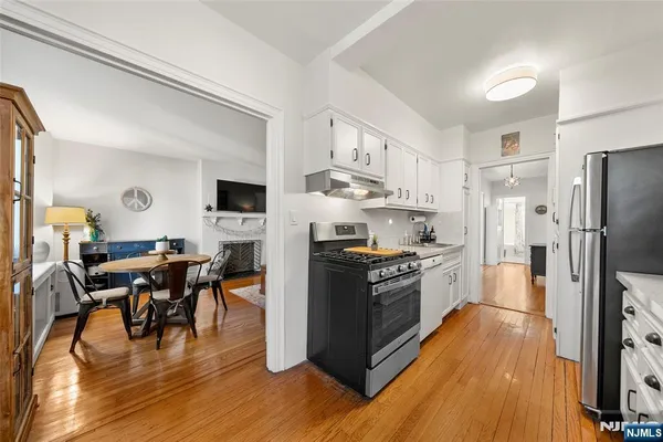 a kitchen with stainless steel appliances a stove a sink a refrigerator and a dining table with wooden floor