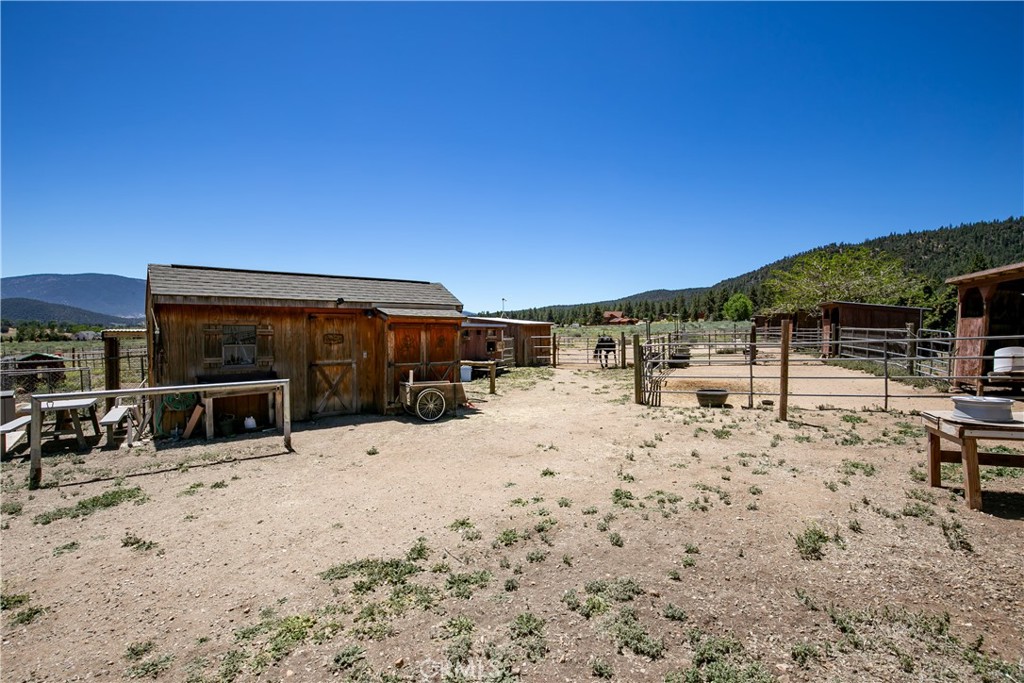 10960 Steinhoff Road Frazier Park, CA 93225 - Photo 14 of 46 A functional ground-level perspective highlighting the property's outdoor equestrian infrastructure. This shot captures the secure cross-fenced corrals, open horse pens, and outdoor staging areas, all framed by a scenic mountain and tree-lined landscape.