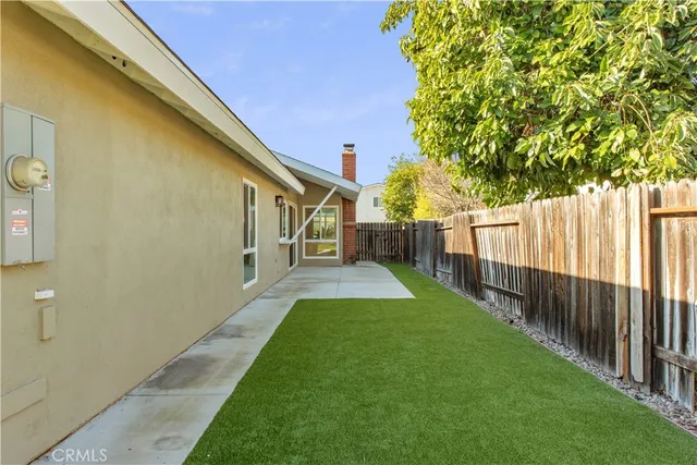 a view of a backyard with wooden fence and large trees