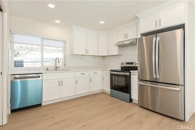 a kitchen with granite countertop white cabinets and stainless steel appliances