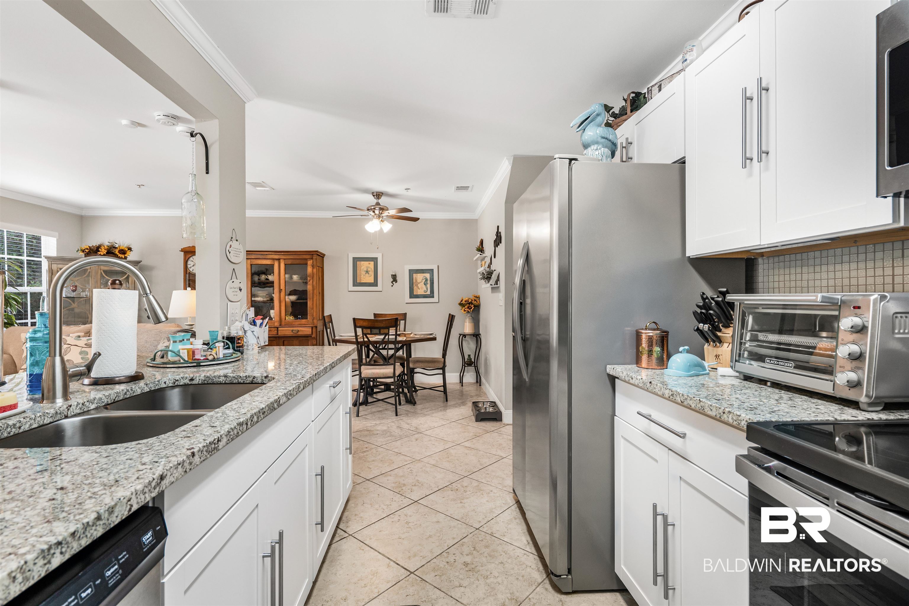 1517 Regency Road, Unit 68 Gulf Shores, AL 36542 - Photo 14 of 43 Kitchen featuring light stone countertops, appliances with stainless steel finishes, crown molding, sink, and white cabinets