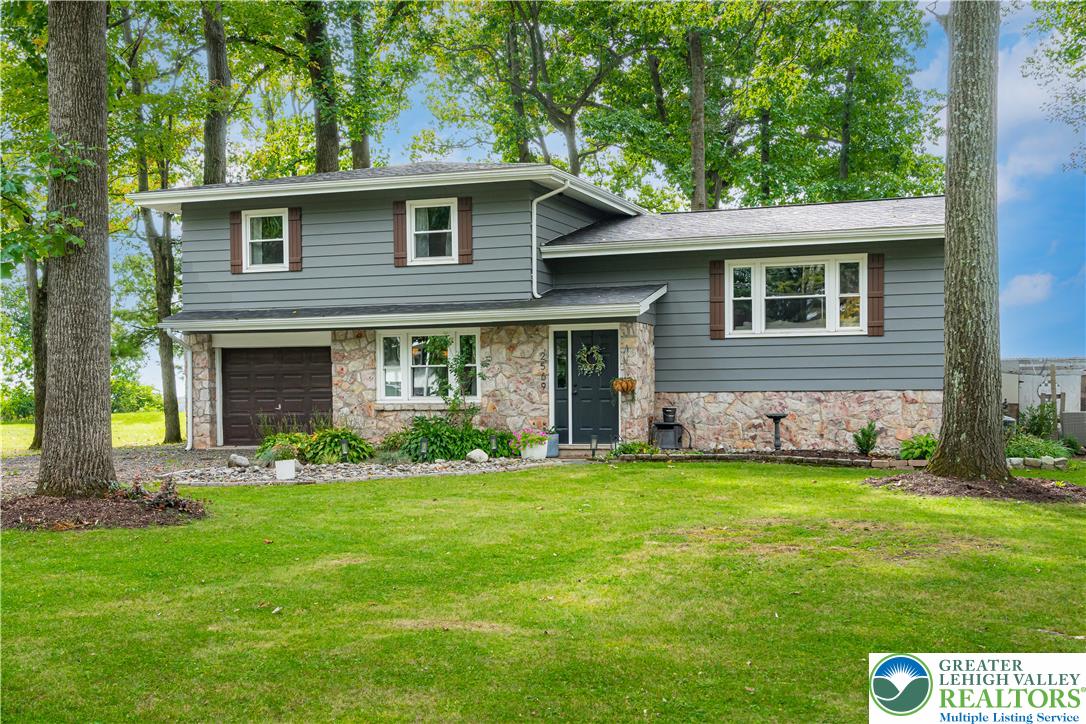 2569 Woods Edge Road Bath, PA 18014 - Photo 1 of 40 Mature trees frame a charming multi-level exterior displaying stone accents and a grassy lawn.