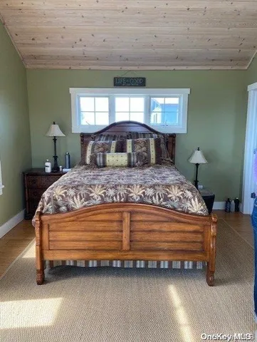 a bedroom with a bed wooden floor and window