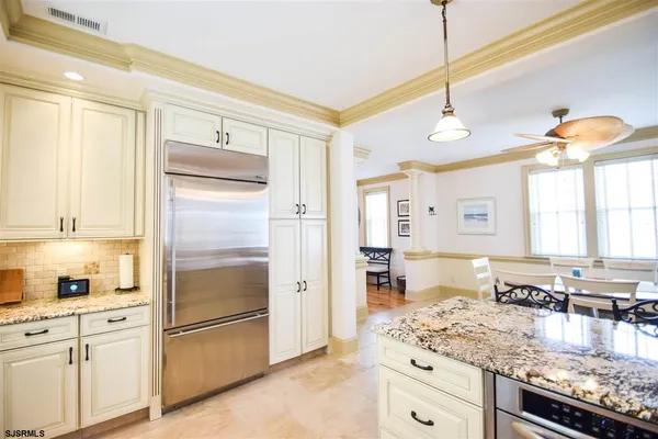 a kitchen with stainless steel appliances granite countertop a refrigerator a oven and white cabinets with wooden floor