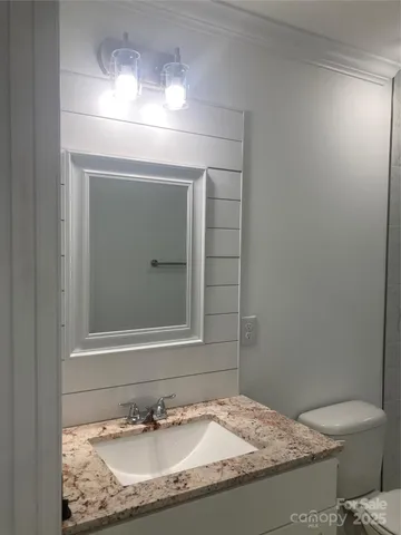 a bathroom with a granite countertop sink and a toilet