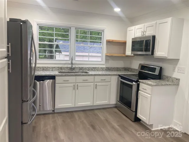 a kitchen with stainless steel appliances granite countertop a stove a sink and a microwave