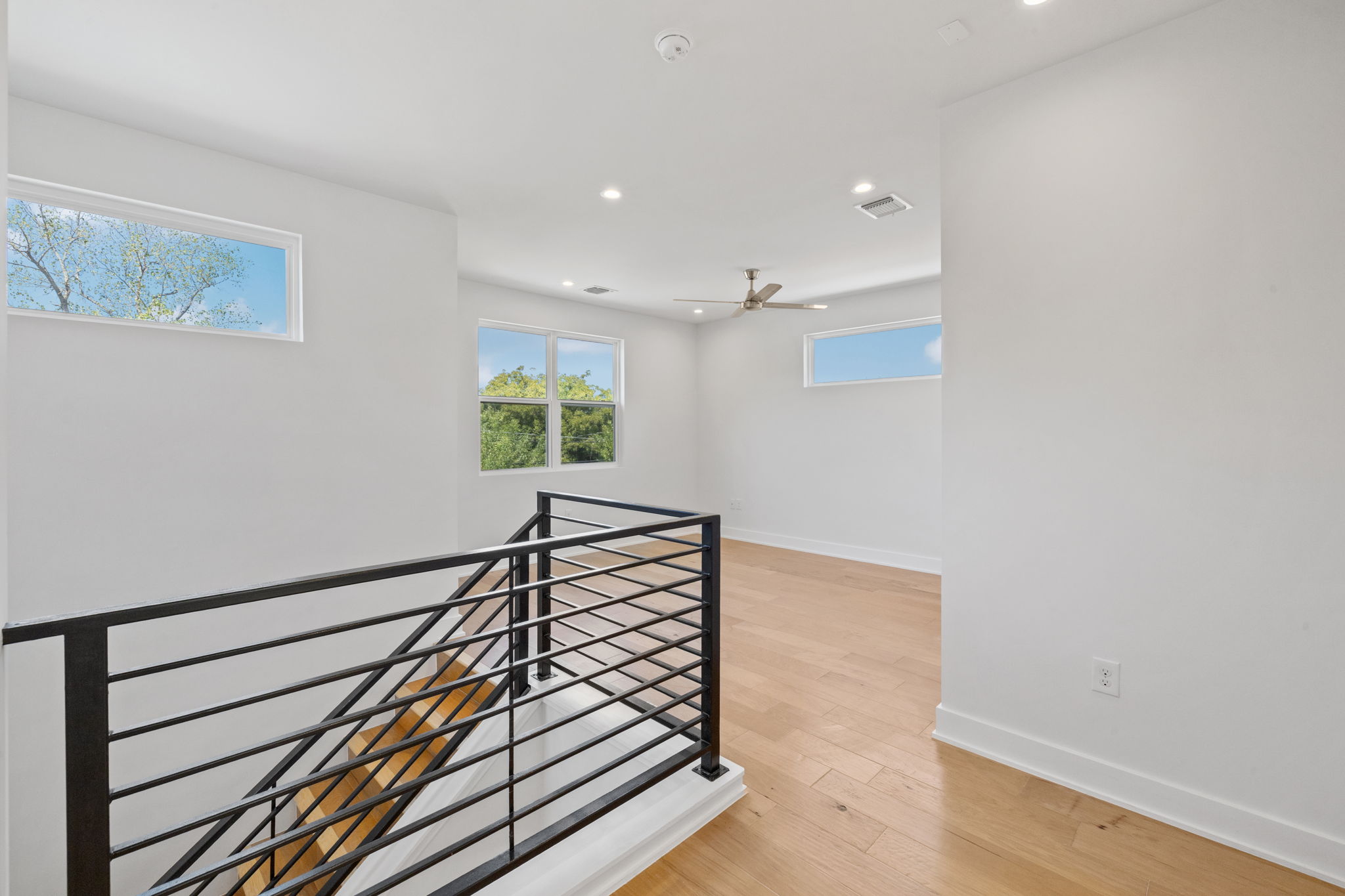 1719 Bunche Road Austin, TX 78721 - Photo 21 of 36 A modern stair landing features clean horizontal metal railings and warm hardwood flooring.