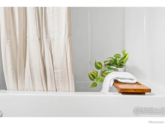 a white vase with flowers and white on a wooden floor