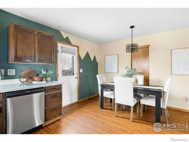 a kitchen with stainless steel appliances kitchen island granite countertop a table chairs and a wooden cabinets