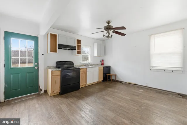 a kitchen with stainless steel appliances a white stove top oven a sink and dishwasher a refrigerator with wooden floor