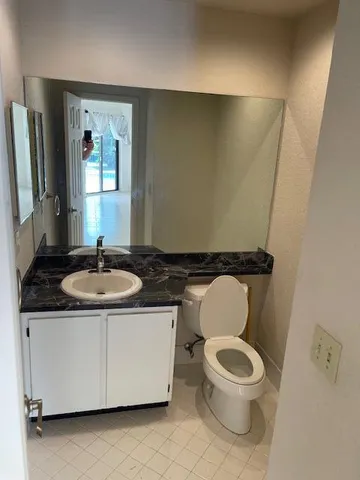 a bathroom with a granite countertop toilet sink and mirror