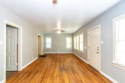 a view of an empty room with wooden floor and a window