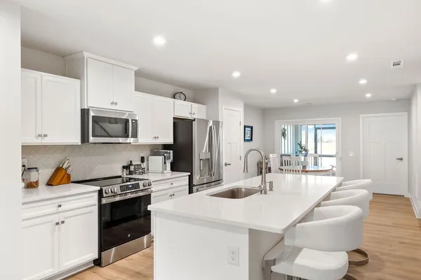 a kitchen with stainless steel appliances a sink a stove a refrigerator cabinets and a dining table