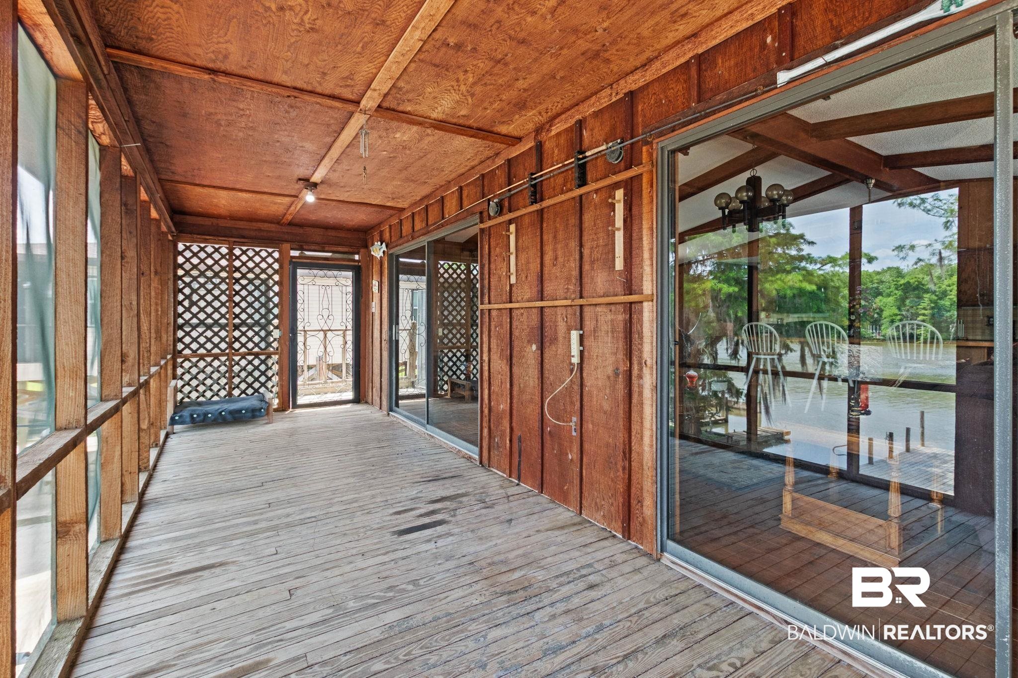 8153 Bryant's Lndg Road Stockton, AL 36579 - Photo 61 of 87 Enclosed outdoor patio featuring wood-finish flooring, wood paneling, wood-frame windows, and a sliding glass door