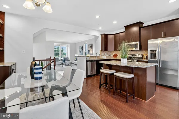 a kitchen with stainless steel appliances granite countertop a table chairs refrigerator and sink
