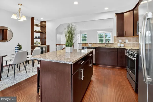 a large kitchen with granite countertop a stove top oven a sink dishwasher a dining table and chairs with wooden floor