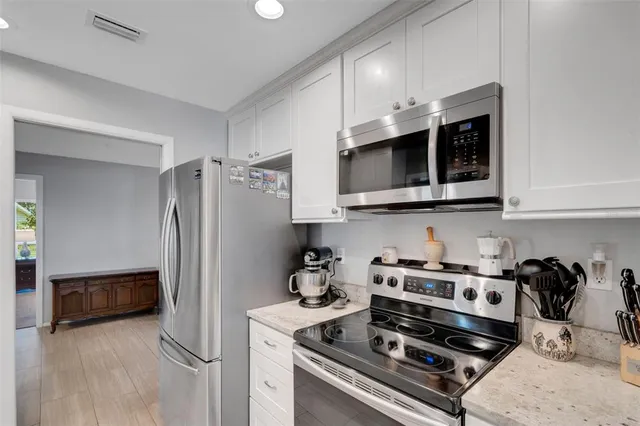 a kitchen with stainless steel appliances granite countertop a refrigerator and a stove top oven