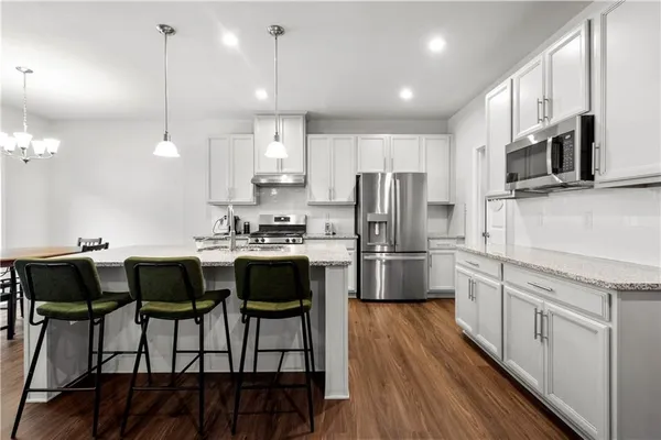 a kitchen with stainless steel appliances kitchen island granite countertop a table chairs microwave and sink