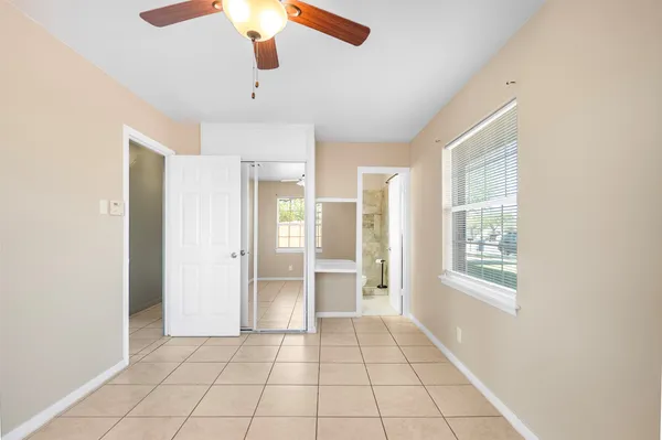 a view of an empty room with window and chandelier fan