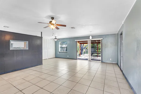 a view of an empty room with window and chandelier fan