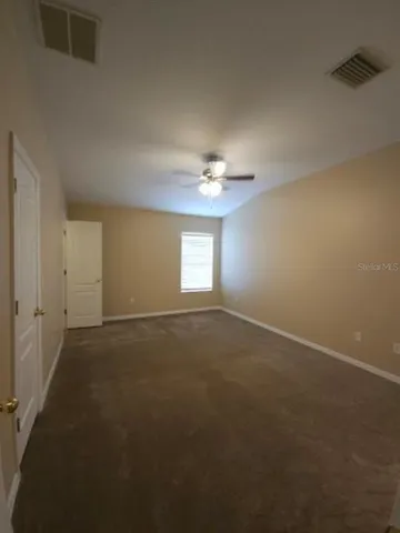 a view of an empty room with a chandelier fan