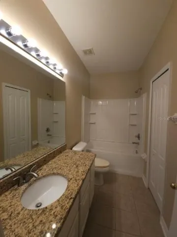 a bathroom with a granite countertop toilet sink and mirror