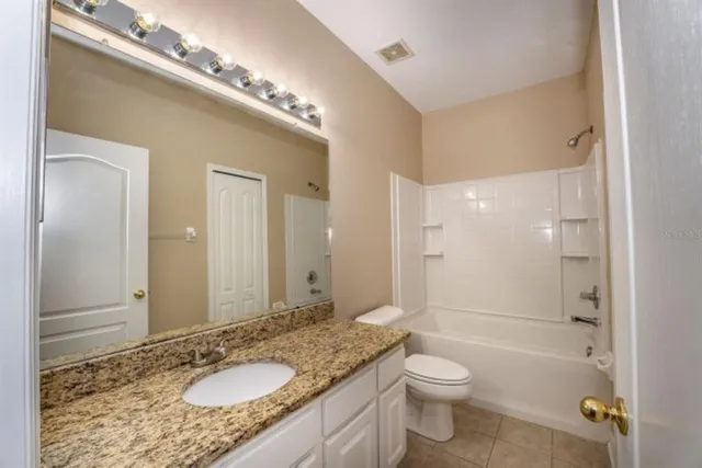 a bathroom with a granite countertop sink toilet a large mirror a shower and a bathtub