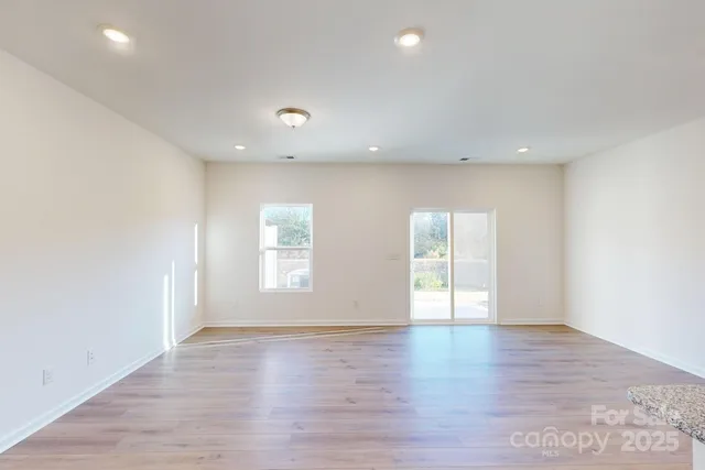 an empty room with wooden floor and window