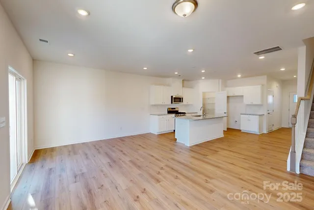 a view of kitchen with kitchen island wooden floor and stainless steel appliances