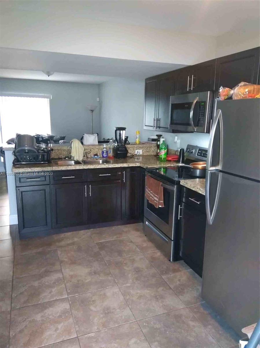 1968 Northwest 4th Court, Unit 323 Miami, FL 33136 - Photo 3 of 12 a kitchen with stainless steel appliances granite countertop a stove refrigerator and microwave