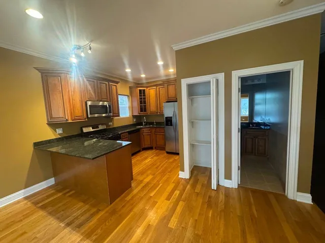 a kitchen with stainless steel appliances granite countertop a refrigerator a stove and a wooden floors